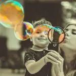 mère et enfant soufflant des bulles de savon colorées ensemble