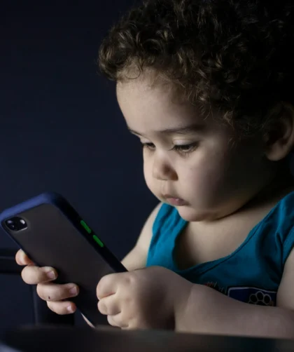 petit enfant concentré sur son téléphone portable dans l'obscurité