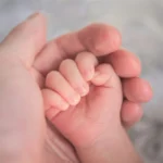 main d'adulte tenant délicatement la main d'un nourrisson
