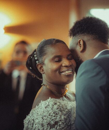 A bride and groom share a joyful moment during their wedding ceremony, captured indoors.
