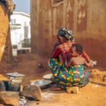 Traditional outdoor cooking scene with African mother and child in a rural village.