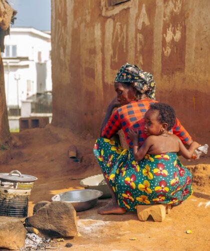 Traditional outdoor cooking scene with African mother and child in a rural village.