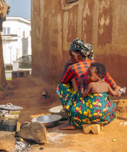 Traditional outdoor cooking scene with African mother and child in a rural village.