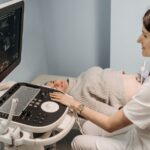 A healthcare professional performing an ultrasound on a pregnant woman in a clinic setting.