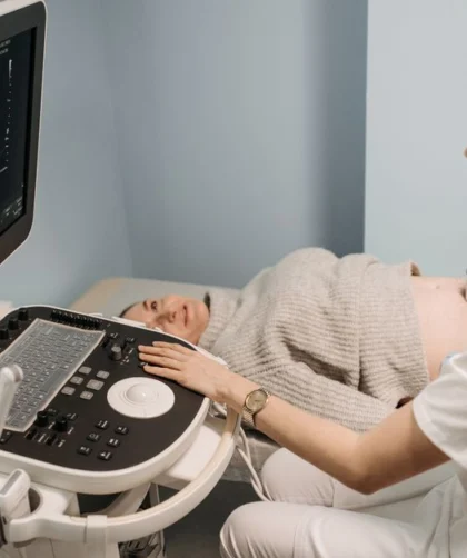 A healthcare professional performing an ultrasound on a pregnant woman in a clinic setting.